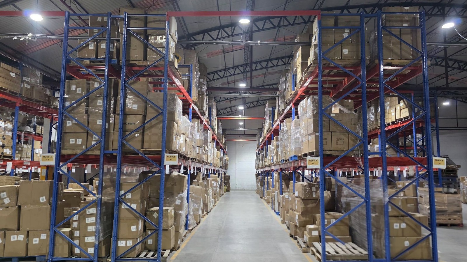 Racks con cajas y tarimas en pasillo amplio